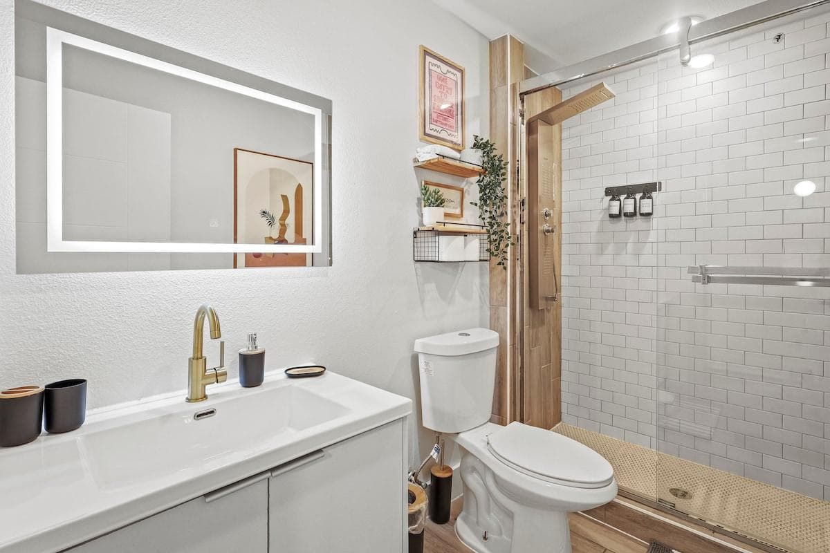 Experience luxury and convenience in our stunning tiled shower, featuring a sleek LED-lit mirror and practical wall shelving. 