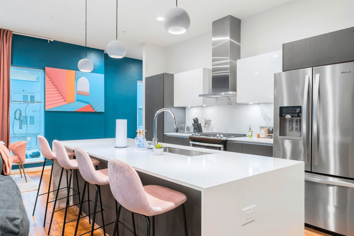 A kitchen featuring a stainless steel Whirlpool fridge, sleek cabinetry, modern sink, stylish furniture, comfy chair, spacious cupboard, polished tap, and built-in oven, offers the convenience of bar top seating.
