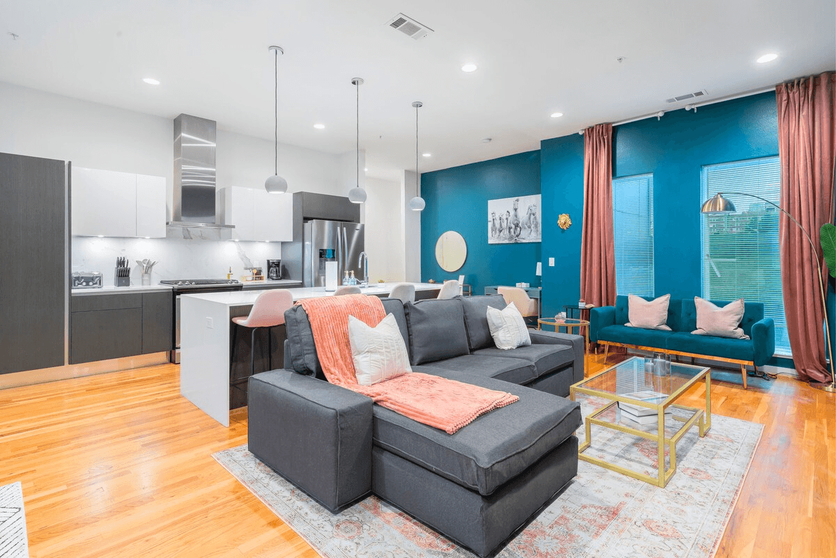 This living room boasts a stylish couch, sleek coffee table, elegant curtains, and a chic chair. Thoughtfully arranged design elements create a warm, welcoming atmosphere, perfect for relaxation and entertaining.